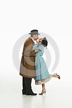 Portrait of happy young couple, man and woman in retro-styled clothes, coats standing and kissing.