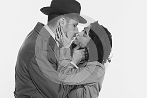 Portrait of happy young couple, man and woman in retro-styled clothes, coats standing and kissing. Monochrome image