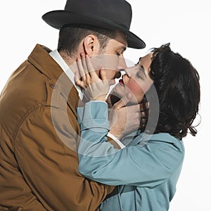 Portrait of happy young couple, man and woman in retro-styled clothes, coats standing and kissing. Tenderness and