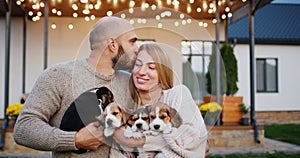 Portrait of a happy young couple with puppies. Standing in front of their beautiful home