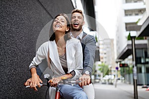 Portrait of happy young couple riding a bike and having fun together outdoor
