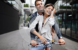 Portrait of happy young couple riding a bike and having fun together outdoor