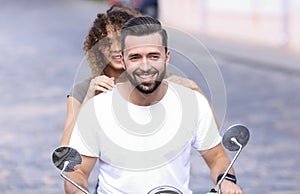 Portrait of happy young couple on scooter enjoying road trip