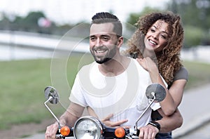 Portrait of happy young couple on scooter enjoying road trip