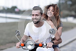 Portrait of happy young couple on scooter enjoying road trip