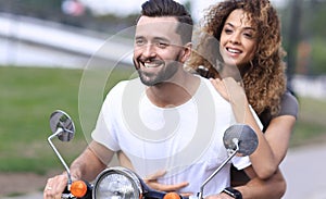 Portrait of happy young couple on scooter enjoying road trip