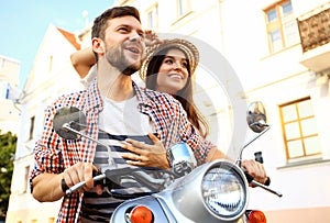 Portrait of happy young couple on scooter enjoying road trip