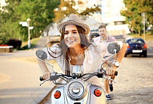Portrait of happy young couple on scooter enjoying road trip