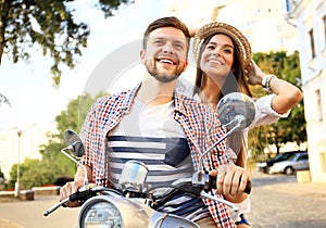 Portrait of happy young couple on scooter enjoying road trip