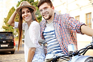 Portrait of happy young couple on scooter enjoying road trip