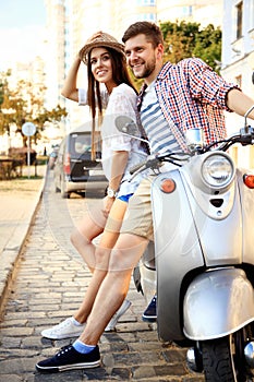 Portrait of happy young couple on scooter enjoying road trip