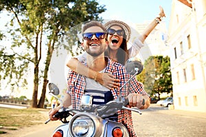 Portrait of happy young couple on scooter enjoying road trip