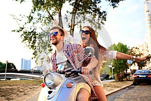 Portrait of happy young couple on scooter enjoying road trip