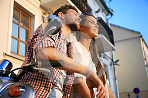 Portrait of happy young couple on scooter enjoying road trip