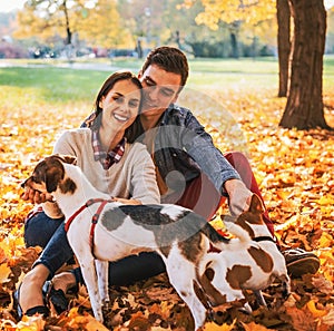 Portrait of happy young couple sitting outdoors in autumn park