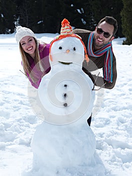 Portrait of happy young couple with snowman