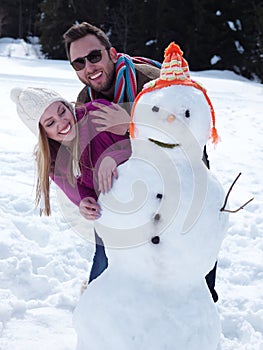 Portrait of happy young couple with snowman