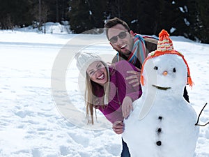 Portrait of happy young couple with snowman