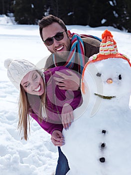 Portrait of happy young couple with snowman