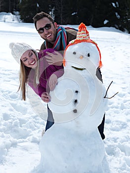 Portrait of happy young couple with snowman