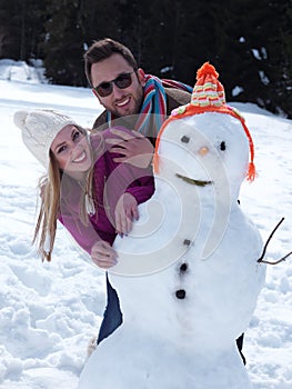 Portrait of happy young couple with snowman