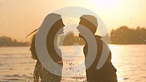 Portrait of happy young couple splashing playfully in the river