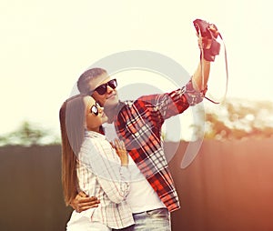 Portrait of happy young couple taking selfie by camera together in summer city park