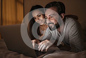 Portrait of a happy young couple using laptop