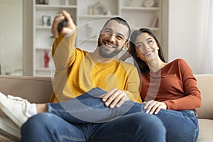 Portrait Of Happy Young Couple Watching Tv And Having Fun At Home