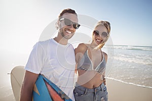 Portrait of happy young couple wearing sunglasses at beach