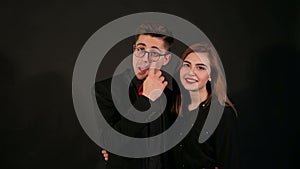 Portrait of a happy young couple who shows thumb up on a black background.