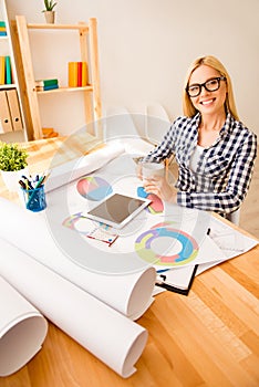 Portrait of happy young engineer drinking tea while working on project