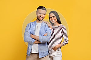 Portrait of happy young european couple posing over yellow studio background