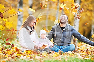 Portrait of happy young family with baby girl in autumn park