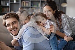 Portrait of happy young family with kids cuddle on sofa