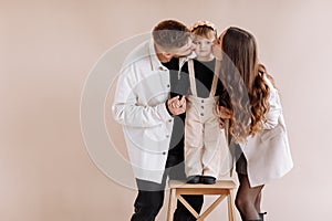 Portrait of a happy young family, with a little adorable daughter. Caring parents holding a baby`s hands. mom and dad kissing