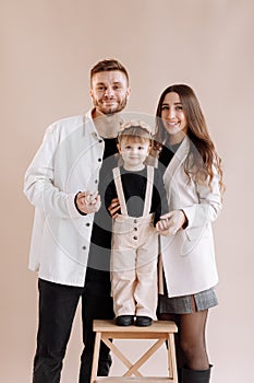 Portrait of a happy young family, with a little adorable daughter. parents holding a baby's hands and hug her. child