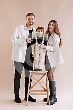 Portrait of a happy young family, with a little adorable daughter. parents holding a baby& x27;s hands and hug her. child