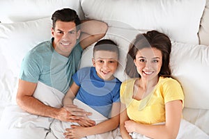 Portrait of happy young family resting in bed