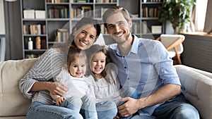 Portrait happy young family sitting on cozy couch together