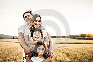 Portrait of a happy young family smiling in the countryside. Concept of family fun in nature