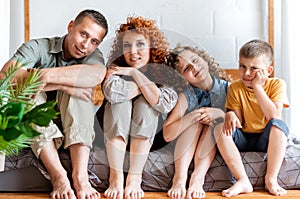 Portrait of a happy young family with two children in bedroom,