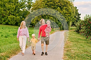 Portrait of happy young family with two little children enjoying good time in apple orchard