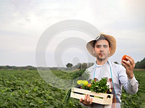 Portrait of a happy young farmer holding fresh vegetables in a basket. On a background of nature The concept of biological, bio