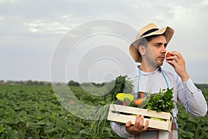 Portrait of a happy young farmer holding fresh vegetables in a basket. On a background of nature The concept of biological, bio