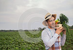 Portrait of a happy young farmer holding fresh vegetables in a basket. On a background of nature The concept of biological, bio