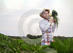 Portrait of a happy young farmer holding fresh vegetables in a basket. On a background of nature The concept of biological, bio