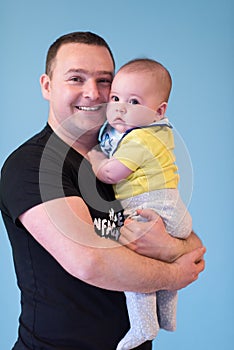 Portrait of happy young father holding baby isolated on blue