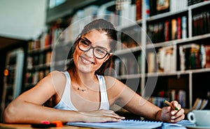 Portrait of happy young female studying in a library. Education study teenager concept