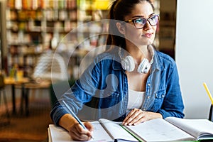 Portrait of happy young female studying in a library. Education study teenager concept